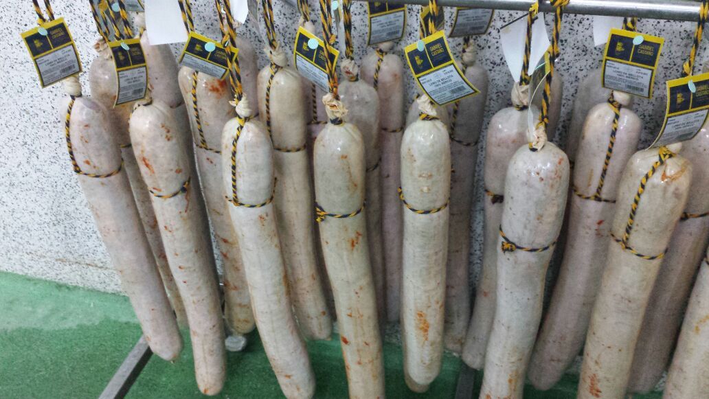 Salchichones ibéricos colgados en el secadero con su etiqueta
